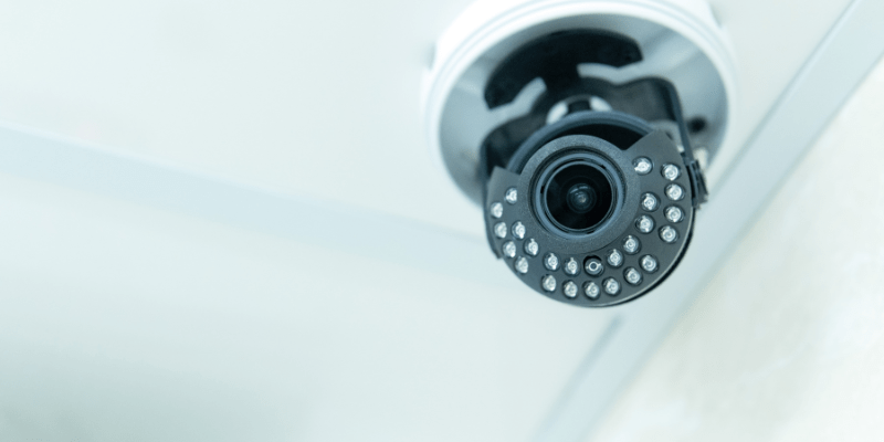 Caméra de surveillance connectée et fixée au plafond, un élément clé des systèmes de sécurité et de monitoring d'un bâtiment intelligent.