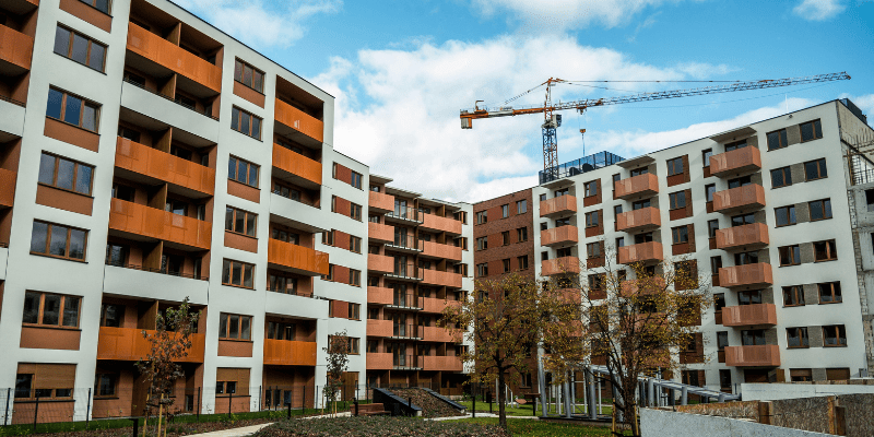 Bâtiments résidentiels modernes avec balcons et espaces verts, une grue en arrière-plan pour signifier un chantier de réhabilitation de logement sociaux.