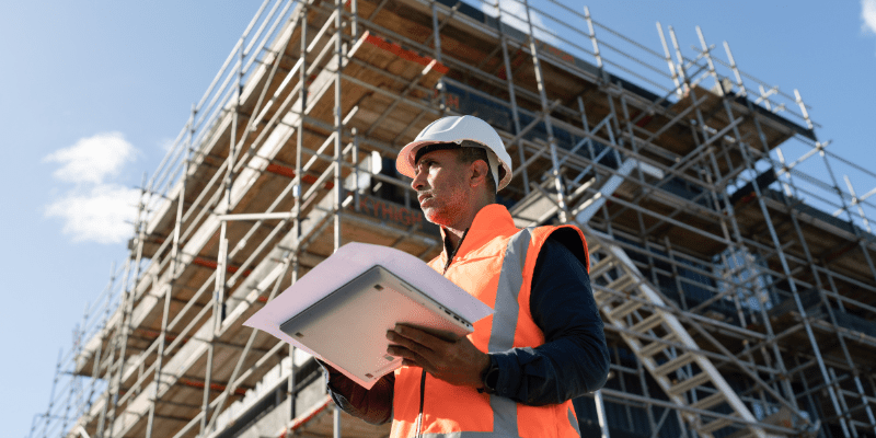 Conducteur de travaux avec tablette et plans sur un chantier de bâtiment en phase d'OPR.