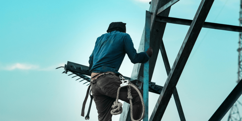 Ouvrier du bâtiment travaillant en hauteur sur une structure métallique.